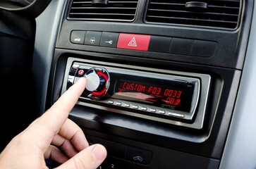 Obraz premium Car audio player and man`s hand. Adjustment player. Closeup view