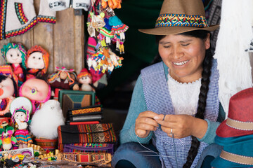Latin woman smiling and weaving with wool in a handicraft shop - obrazy, fototapety, plakaty