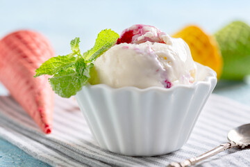 Ball of vanilla ice cream with berry sauce.