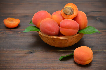 basket with ripe fruits, apricots on a wooden background