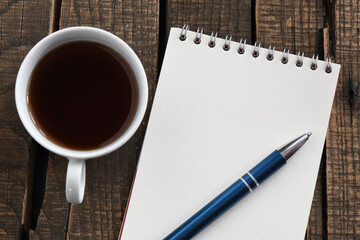 Blank notepad and coffee cup on office wooden table