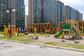 Fototapeta na wymiar Children's playground in a modern complex of apartment buildings on a sunny day. The territory of the kindergarten.With outdoor amenities