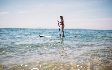 Fototapeta na wymiar Photo of woman paddling SUP board