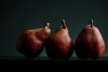 three red pears on a black table