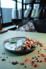 georgian salad with tomato, cucumber or walnut and red wine in glass on table