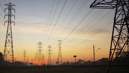 Large utility power line towers in the foreground and sunset in the background