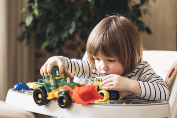 Cute little boy playing with kinetic sand, toy car and tractor. Development of fine motor skills....