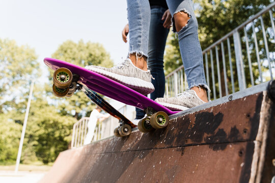 Children girls friends ready for ride on penny board on skateboard park playground. Sports equipment for kids.