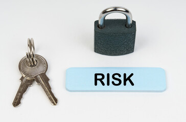On a white surface there is a lock, keys and a blue sign with the inscription - Risk