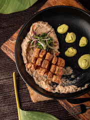 Chicharrón sobre cama de frijol refrito