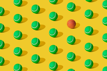 Arranged of green rubber tennis balls and one basketball on yellow pastel background. Pattern.