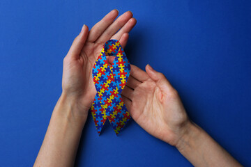 World Autism Awareness Day. Woman with colorful puzzle ribbon on blue background, top view