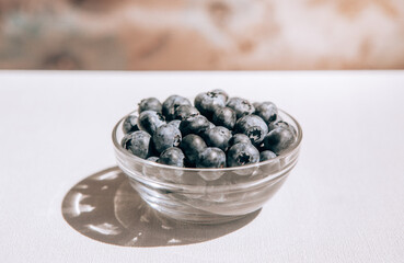 Fresh blue blueberry in bowl on light table, organic food in summer
