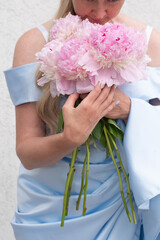 Obraz na płótnie Canvas bride in a blue wedding dress with a bouquet of pink peonies, pastel paradise