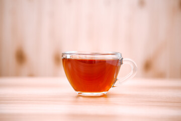Glass cup of black tea on the wooden table, hot drink