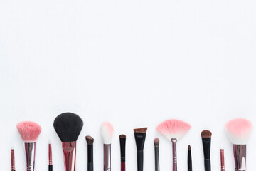 Minimal makeup brushes lined up on the bottom on white