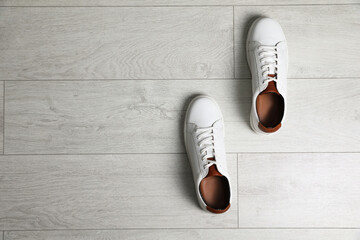 Pair of stylish sports shoes on white wooden floor, flat lay. Space for text