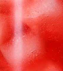 Glass of refreshing drink with ice cubes as background, closeup