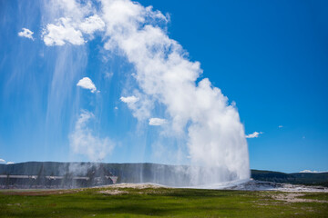 Visitors watch the famous geyser Old Faithful on a sunny day at Yellowstone National Park, which is the first national park in the U.S.