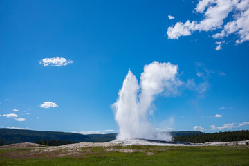 Visitors watch the famous geyser Old Faithful on a sunny day at Yellowstone National Park, which is the first national park in the U.S.