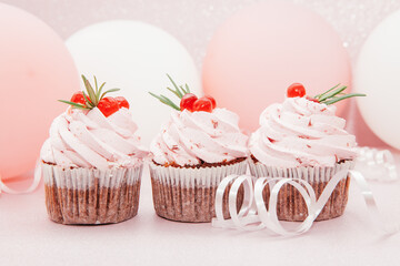 Three strawberry pink cupcakes on glitter background with air balloons