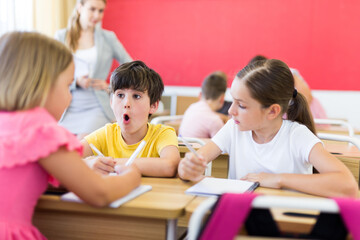 Fototapeta premium Focused tweens working in small groups during lesson at school, discussing assignment given by teacher. Teamwork concept