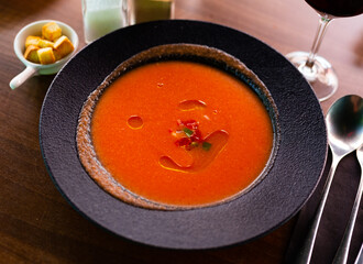 Black plate of traditional Spanish refreshing pureed vegetable soup Gazpacho served with crispy...