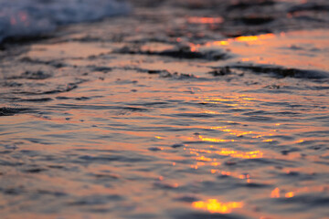 Wave splash at sunset close up. Ocean water in sunlight in motion. Abstract sea background