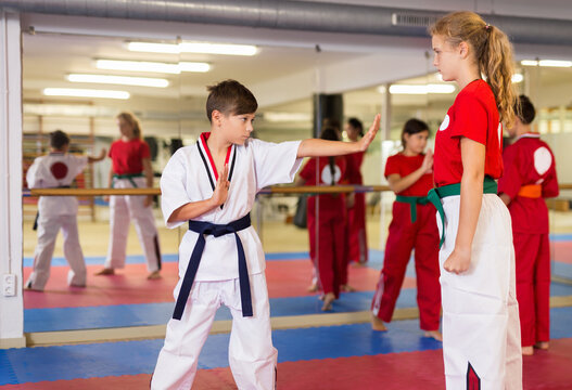 Young children sparring in pairs to practice new moves in karate class