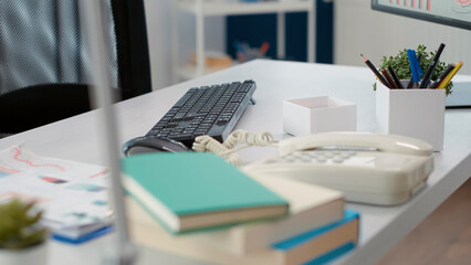 Empty company desk with landline phone and documents to work on financial strategy with business charts for startup growth. Nobody at table with professional computer. Close up.