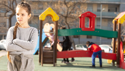 Obraz premium Portrait of offended girl not playing with friends after quarrel on playground. High quality photo