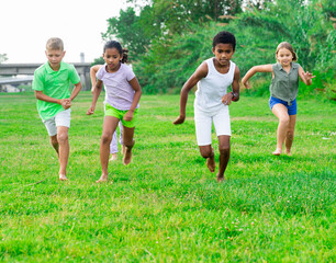 Positive kids playing active games in summer park chasing each other