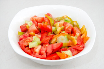 White plate with fresh tomato and sweet pepper salad. Close-up