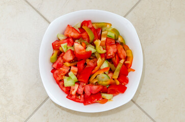 White plate with fresh tomato and sweet pepper salad. Close-up