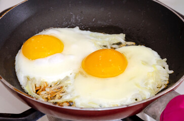 Fried eggs with onions in a pan. Close-up