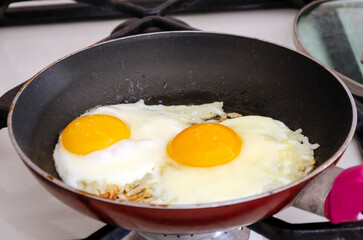 Fried eggs with onions in a pan. Close-up