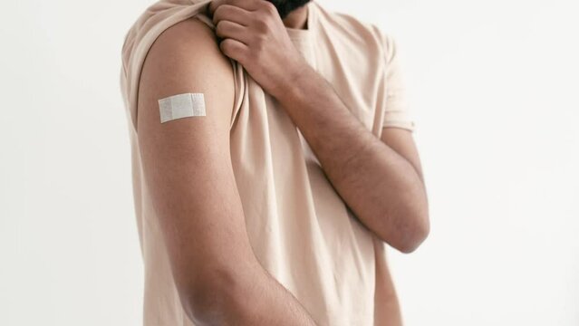 Vaccination and prevention concept. Close-up of male shoulder, showing bandage plaster on arm after getting vaccination, immunization for viruses, stand on isolated white background, thumb-up gesture