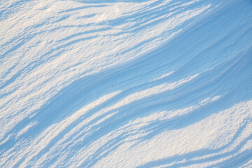 Beautiful winter background with snowy ground. Natural snow texture. Wind sculpted patterns on snow surface.