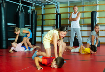 Sportive preteen kids practicing in pair self-protection in class with teacher
