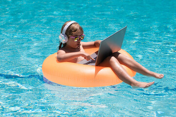 Child swimming on an inflatable ring with a laptop water pool. Child online study or working on tropical sea beach. Technology for life concept.