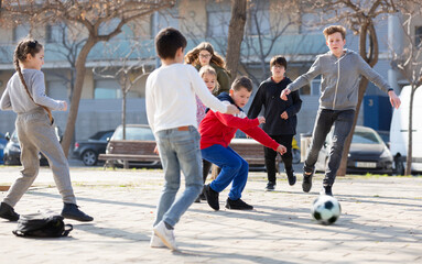 Fototapeta premium Company of glad children playing football on the street. High quality photo