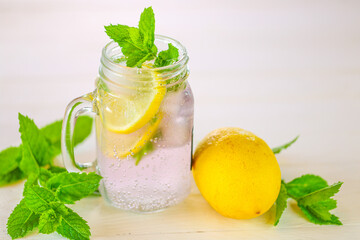 Lemon mint water with ice in a transparent misted mug.Citrus cocktail with mint leaves. Sassy lemon water.Lemon summer drink.Dietary lemon drink.Sprig of mint in a glass with a cocktail.