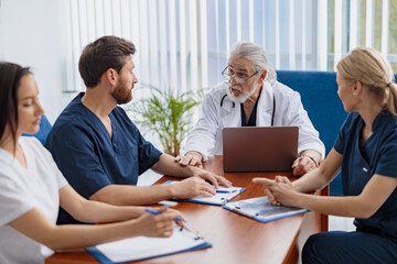 Fototapeta premium Group of doctors sitting at meeting table in conference room during medical seminar