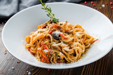 Spaghetti with vegetables in tomato sauce on wooden table