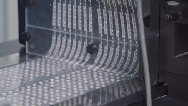 Close-up of automated machine packing pills into blister containers. the packaged tablets in plastic packs are moving on the conveyor. assembly line in the process at chemical factory.