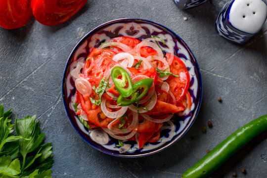 Tomato salad with red onion, achik chuchuk, uzbek cuisine top view on grey table