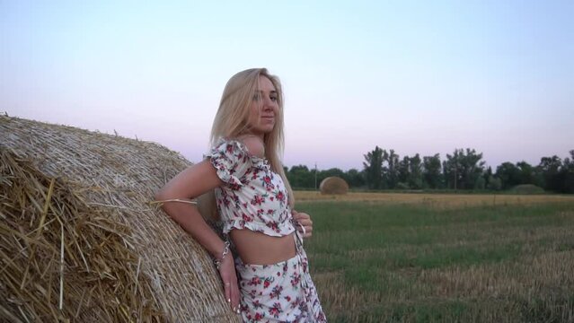 Attractive, sexy blonde in a flower dress near a haystack