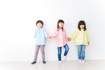 壁に並ぶ3人の幼稚園児