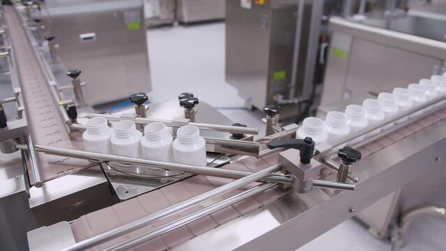 Empty containers on the drug assembly line. plastic vials move on the conveyor belt in the pharmaceutical production company.