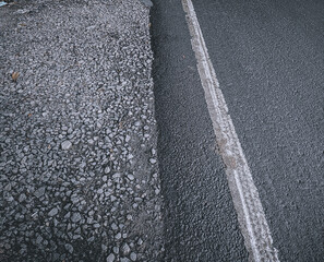 Fototapeta premium Side by side asphalt road and gravel road background